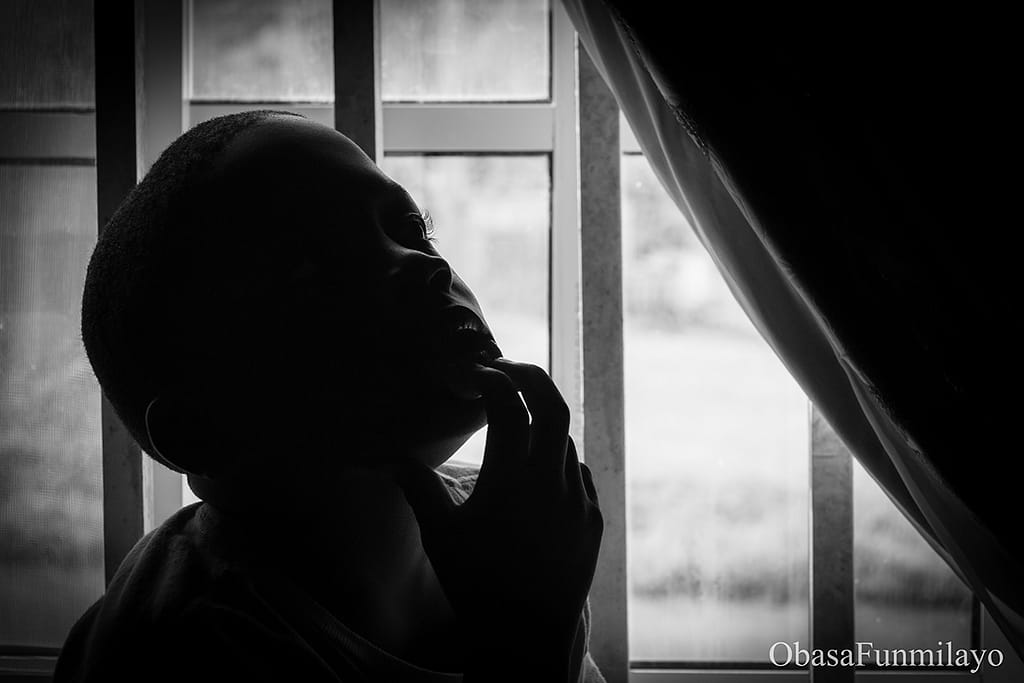 image of a boy silhouetted by light coming from the window-background