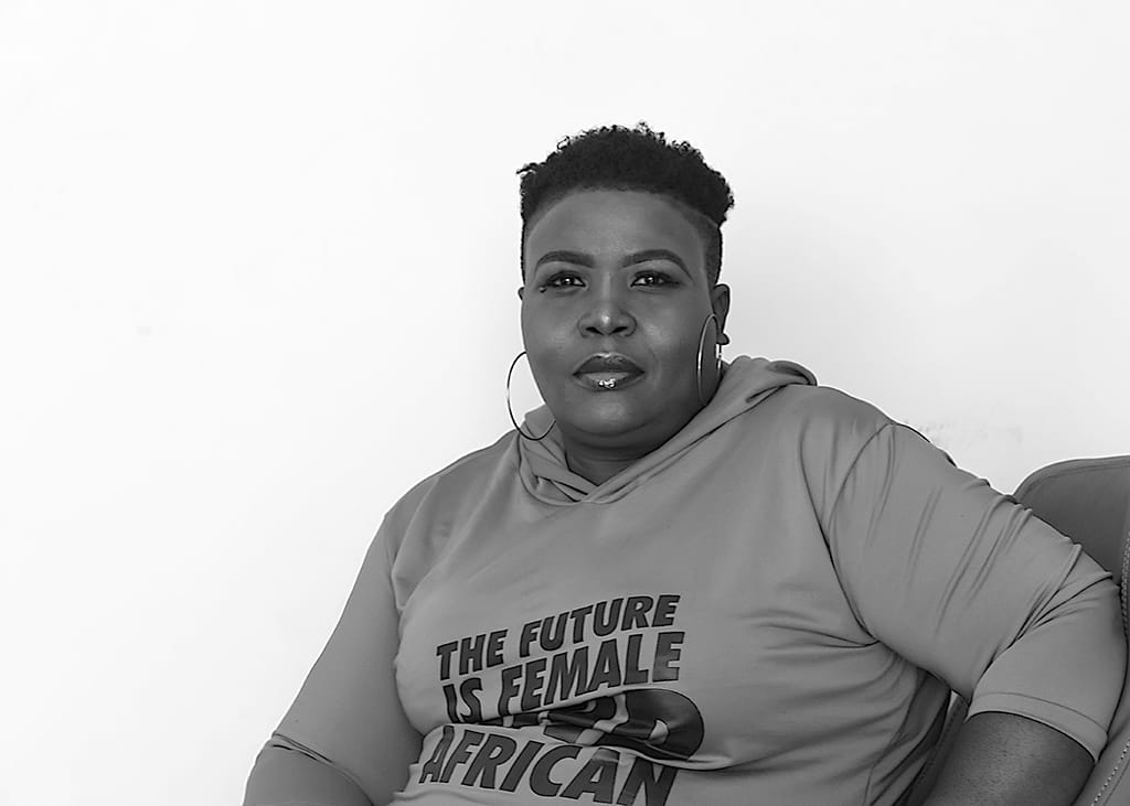 portrait of a woman staring at a camera as she poses, sitting on a leather arm chair