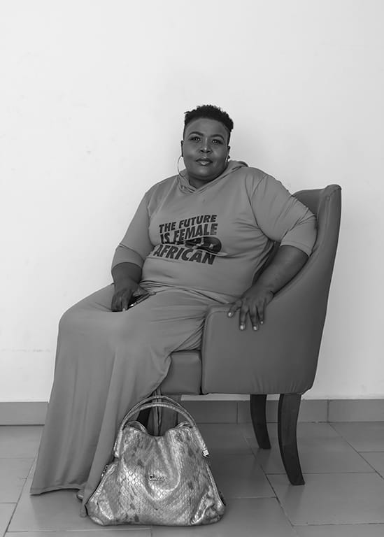 portrait of a woman staring at a camera as she poses, sitting on a leather arm chair